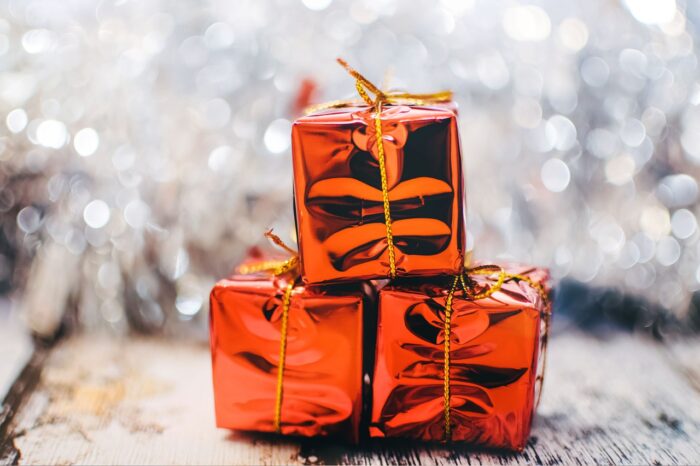 Three gifts in a stack, wrapped in red foil against a snowy background