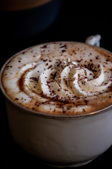 Closeup of a cup of hot chocolate with swirled whipped cream and chocolate shavings