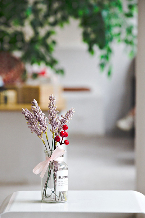 Lavender and red berries in a glass jar near a window