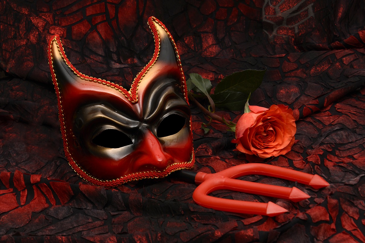 Red devil mask with black eye circles next to red trident and red rose