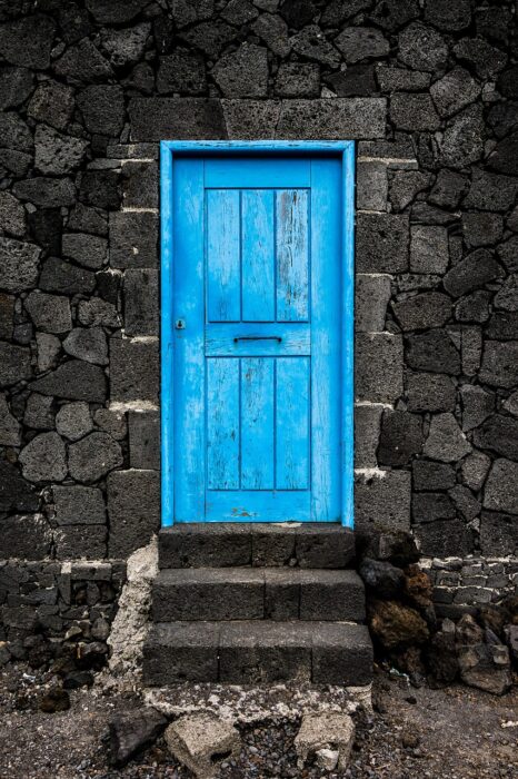 Turquoise door in middle of gray stone wall