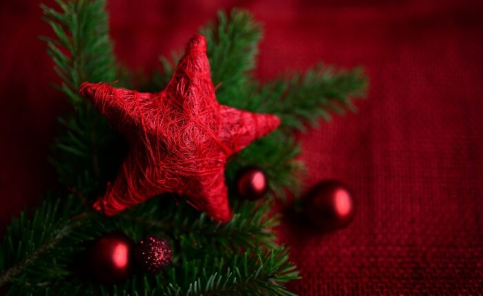 Red star atop a CHristmas tree with red background and red ornaments