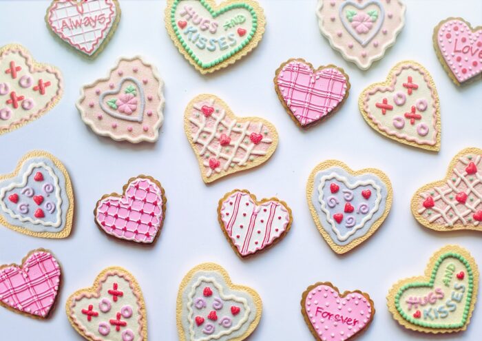 Heart-shaped sugar cookies decorated with pink, white and gren icing and messages like "Love" and "XOXOX"