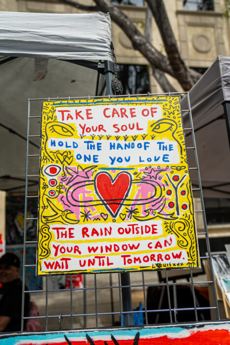 Painted posted says, "Take care of your soul. Hold the hand of the one you love. The rain outside your window can wait until tomorrow.