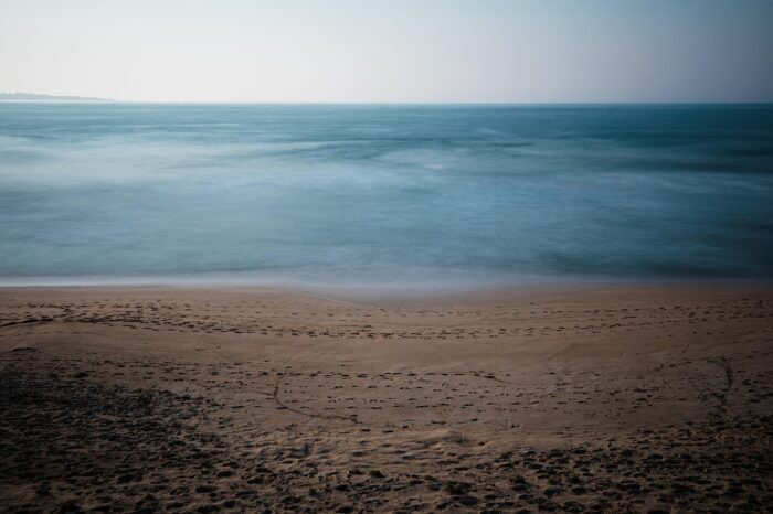 Blue ocean with a vacant, sandy beach and a distant horizon