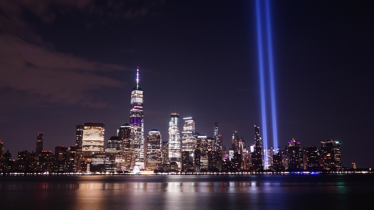 Blue light tribute to the Twin Towers where they once stood, against the night sky in Manhattan skyline.