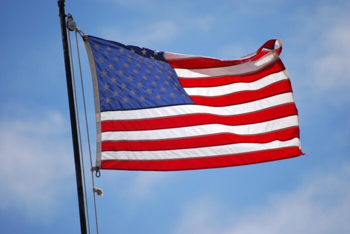American flag against a blue sky with clouds.