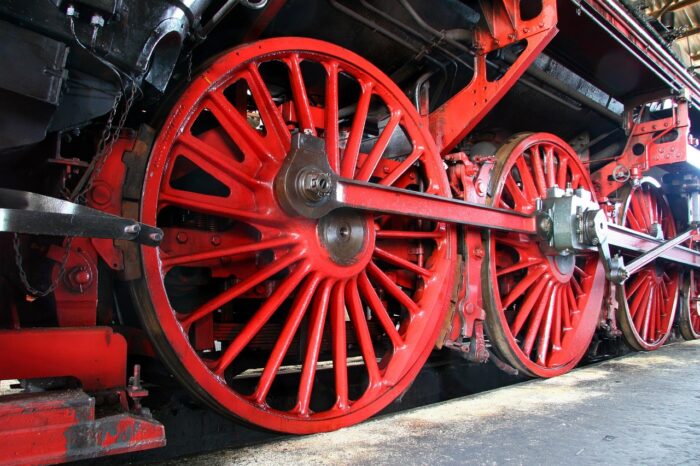 Closeup of red train wheels on a steam locomotive.