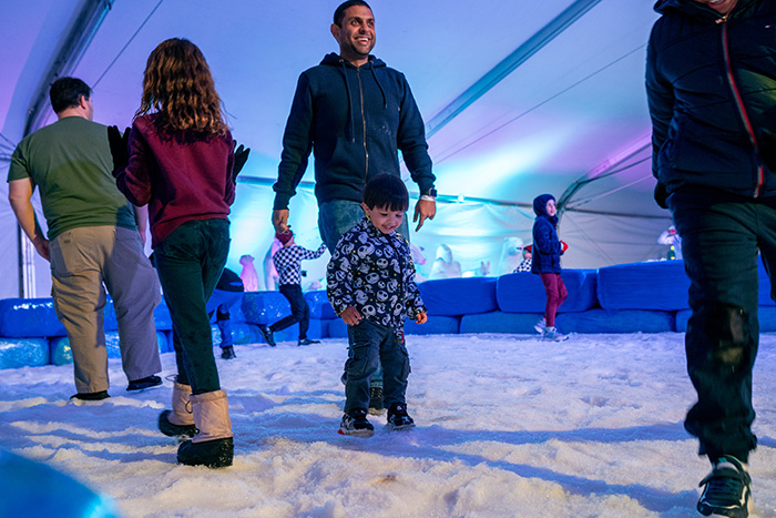 Father and his small son ice skate on snow-covered rink.