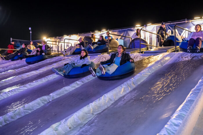 Smiling ice tubers slide down 150-foot ice slide.