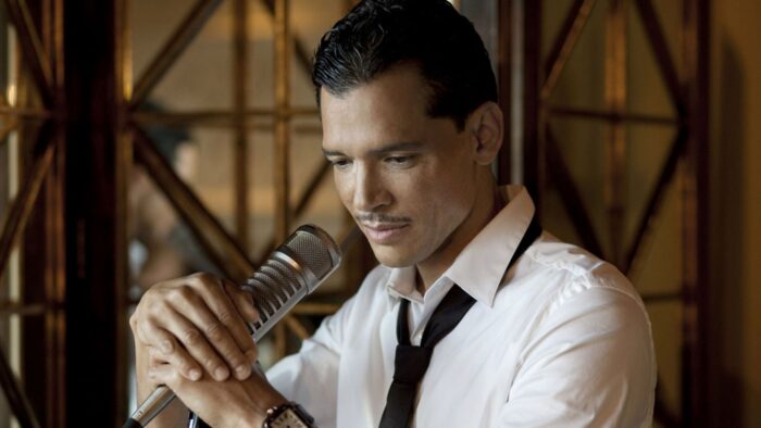 El DeBarge, in a white shirt with a black necktie, cups a mic in his hand