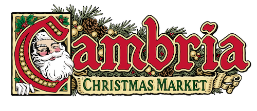 Cambria Christmas Market logo shows "Cambria" in red script letters, with "Christmas Market" beneath in green, against a background of holly.