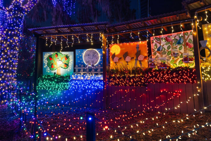 Twelve Days of Christmas murals in lights with strings of blue, red, gold and green lights from each.