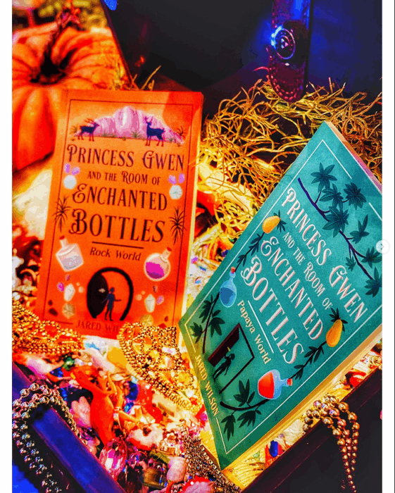 Copies of "Princess Gwen and the Room of Enchanted Bottles", in hardback, with orange and turquoise covers.