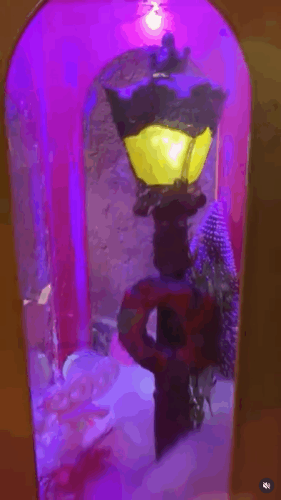 Lighted lantern with Christmas wreath against magenta background.