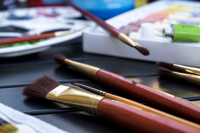 Variety of paintbrushes resting on a collection of artists' supplies.