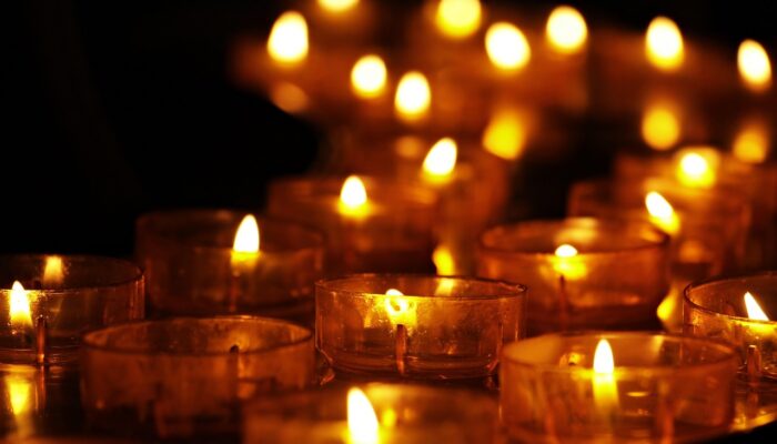 Fifteen votive candles in amber glass glow against the darkness