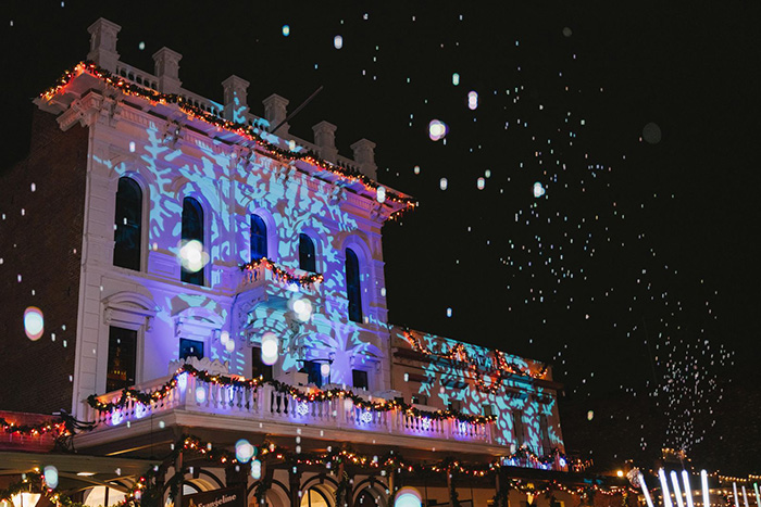 Snowflake pattern in lights on a downtown building, with red and green lights on the adjacent building