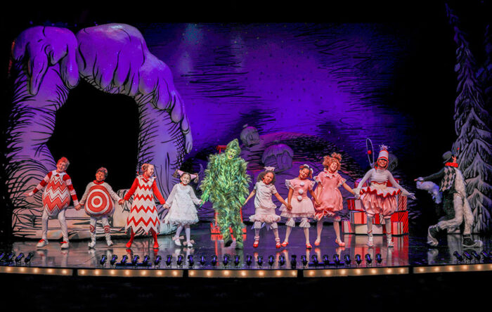 Holding hands, with the Gerinch in tghe middle, the cast of How the Grinch Stole Christmas! appear onstage.