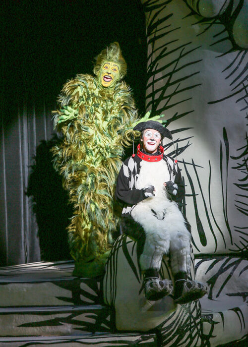 Andrew Polec, in green Grinch costume, sings onstage with Tommy Martinez, in his dog costume as Young Max.