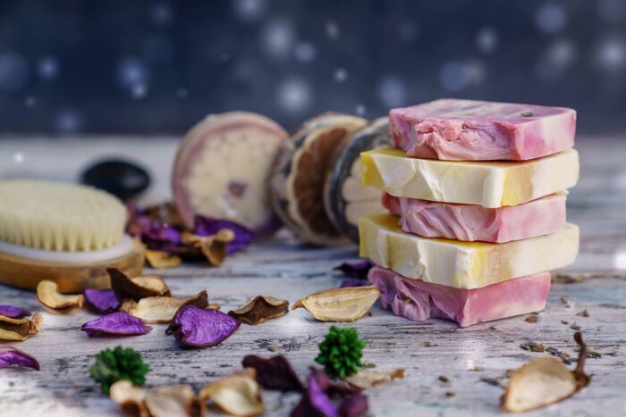 Stacks of handcut pink and white soaps on a table with purple and white flower petals