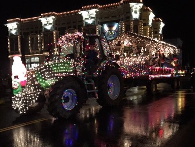 Lighted green tractor travels down Main Street.