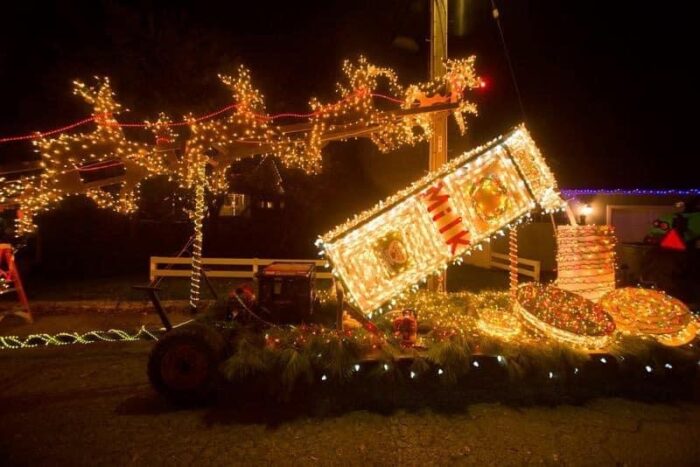 Santa's reindeer leap over a giant carton labeled "MILK" and a plate of cookies on a lighted parade float.