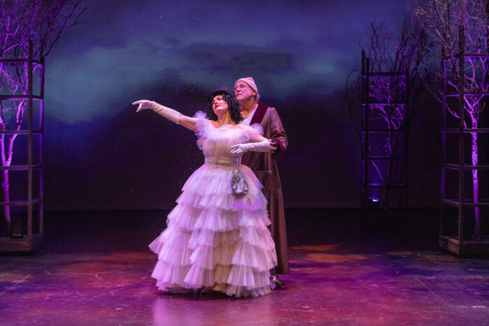 Trisha Miller, as Ghost of Christmas Past, conducts Scrooge (Geoff Elliott) through a starlit forest.