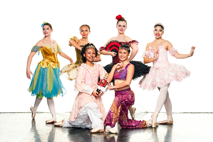 Members of The Nutcracker troupe, including a Spanish dancer, sugarplum and Arabian dancer, flank "Clara" as she holds the nutcracker and kneels center stage.