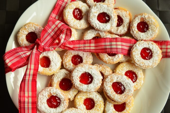 Plate of jam thumbprint cookies with a red gingham ribbon around them