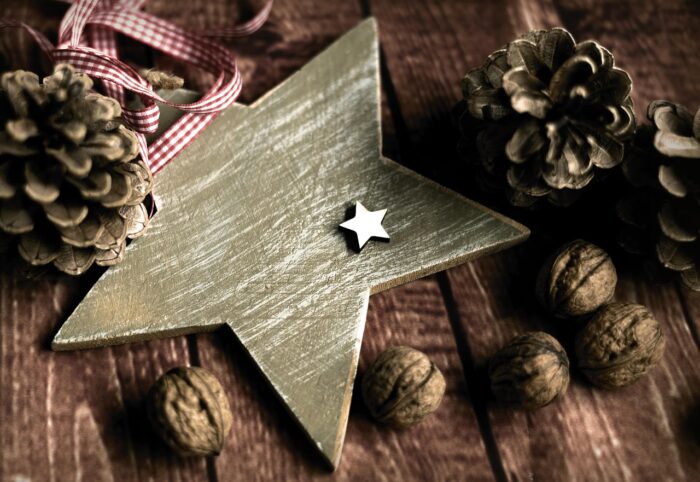 Gilded wooden star with a red-and-white ribbon, pinecones and walnuts.