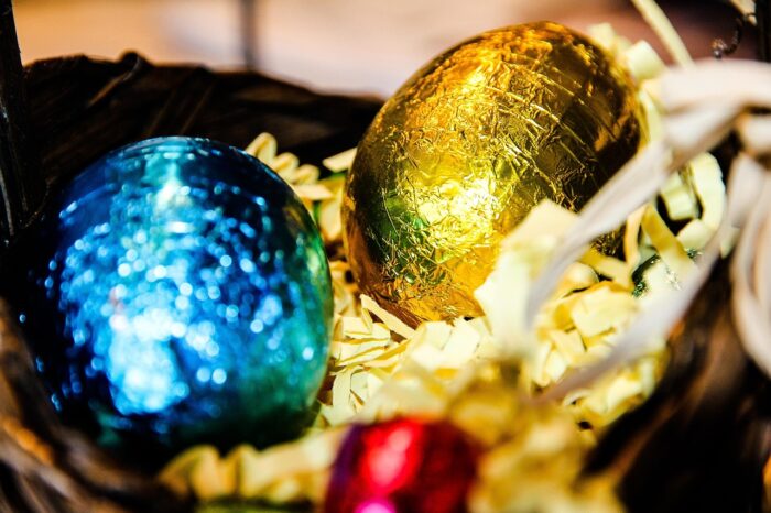 Closeup of chocolate Easter egg candies in blue and gold foil in an Easter basket