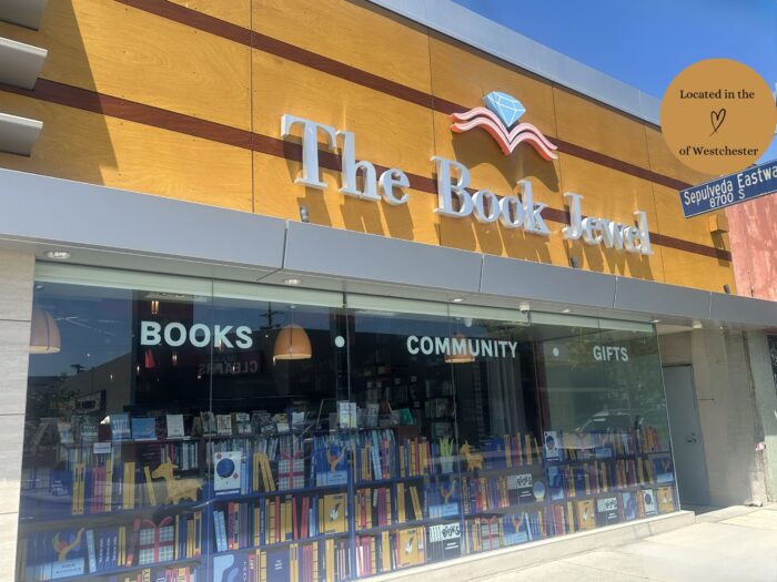 Facade of The Book Jewel shows filled bookshelves beyond the plate-glass window. Sign over door advertises, "Books, Community, Gifts."
