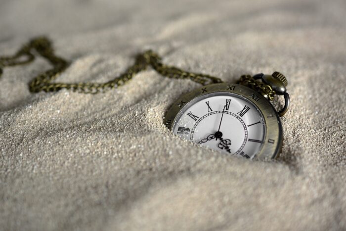 Pocket watch with chain half-buried in sand