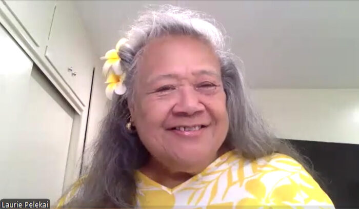 Likohina's Tropical Butters Proprietor Laurie Pelekai, in a yellow dress with white plumeria in her hair, smiles as she shares the story of her small business.